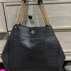 Black/gold Coach shoulder bag with embossed print.